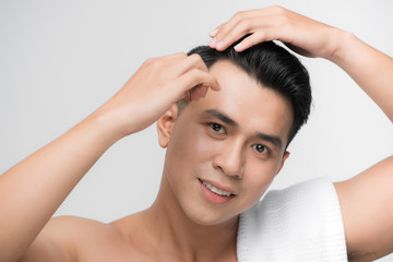 beauty, grooming and people concept - smiling young man brushing hair with comb over white background