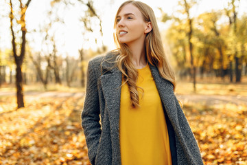 Happy young girl smiling with autumn yellow leaf in Park