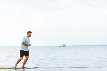 Fototapeta na wymiar man running by sea beach barefoot