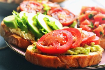Bruschetta on a dark table background. Bruschetta with grilled  tomatoes, mozzarella and avocado. Delicious vegetarian healthy sandwiches. Tasty snack.