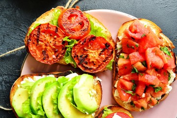 Bruschetta on a dark table background. Bruschetta with grilled  tomatoes, mozzarella and avocado. Delicious vegetarian healthy sandwiches. Tasty snack.