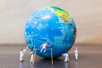 Miniature people : Painters are painting  The globe on wooden background
