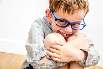 cute child giggling, hiding his missing tooth mouth in knees