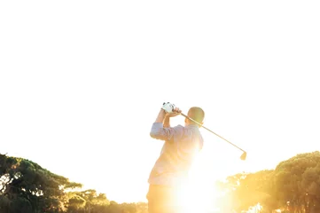 Poster Male golf player teeing off golf ball from tee box to beautiful sunset © karrastock