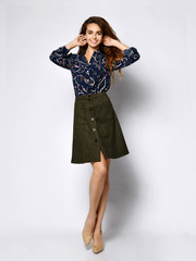 cheerful young woman posing in solitude, in a blue silk blouse with floral patterns, a dark short...