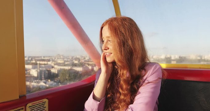 Portrait of sun kissed girl enjoying ity sunset from a window of funicular or ferris wheel cabine.