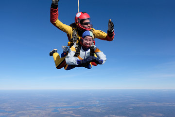 Fototapeta na wymiar Skydiving. Tandem jump. A man and a woman are in the sky.
