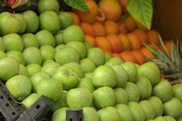 Perspective view of a Granny Smith Apples and  on a street grocery counter in old town. Grapefruit also shown on a minor portion.