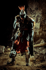 Silhouette of a powerful knight in the armor with the hammer. Dungeon on the background.