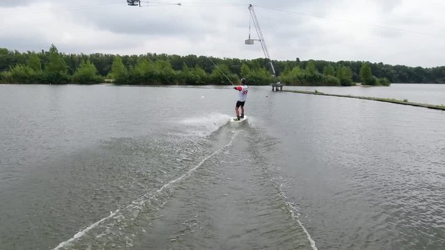 Gliding on the water, using a board, wakeboarding on a cloudy summer day