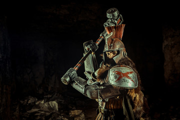 Attack of a powerful knight in the armor with the hammer. Dungeon on the background.