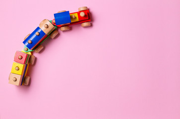 Wooden toy train with colorful blocks on light pink background