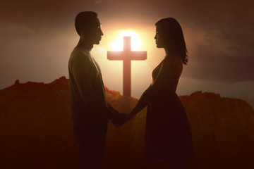 Asian couple holding hands with Christian cross