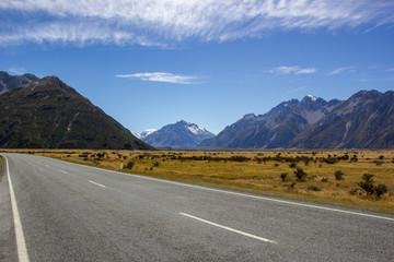 asphalt mountain road near Lake Pukaki near Mount Cook, on a background of blue sky with clouds, Mount Cook, South Island, New Zealand