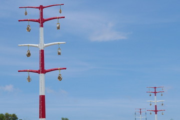 Red and white electrical pole with blue sky background.