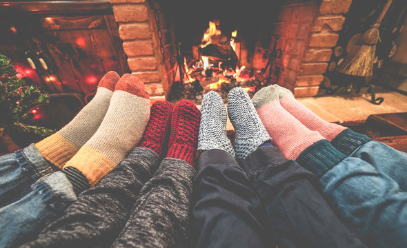 Legs view of happy family lying down next fire place wearing warm wool socks - Winter, holiday, love and cozy concept - Focus on feet