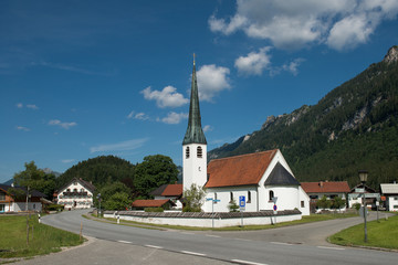 Fototapeta na wymiar Graswang, Bavaria, Germany - July 17, 2019; Picturesque white church in a sunny mountain landscape in the south of Germany