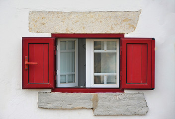 an old red window in a white wall
