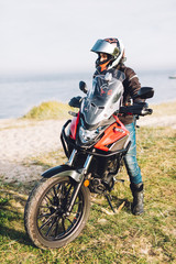 Fototapeta na wymiar Woman on a motorbike looking at the ocean view. Adventure trip