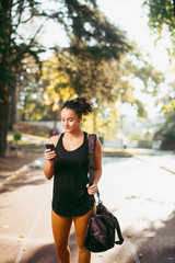 Portrait of young sporty woman using phone outdoors. Beautiful woman in sportswear.