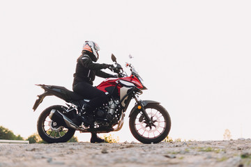 Fototapeta na wymiar Woman standing on roadside with a motorbike. Motorcycle trip