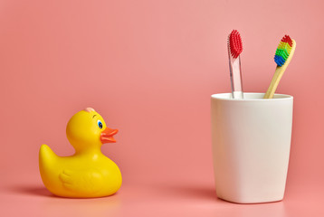 Two toothbrush and duck toy, copy space. Personal care tool for protect oral cavity, remove plaque...