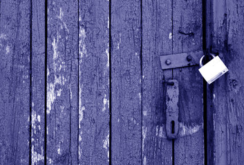 Grungy wooden door with lock in blue tone.