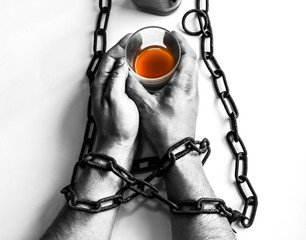Man's hands in old rusty chains near the bottle. Addicted to alcohol. Dangerous habit. - obrazy, fototapety, plakaty