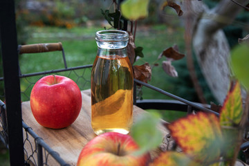 Fresh apple juice in the bottle on the wooden tray, outdoor