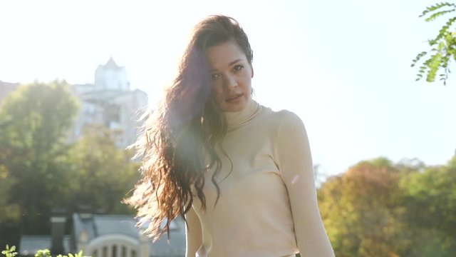 Young adult female looking at camera, sitting against park