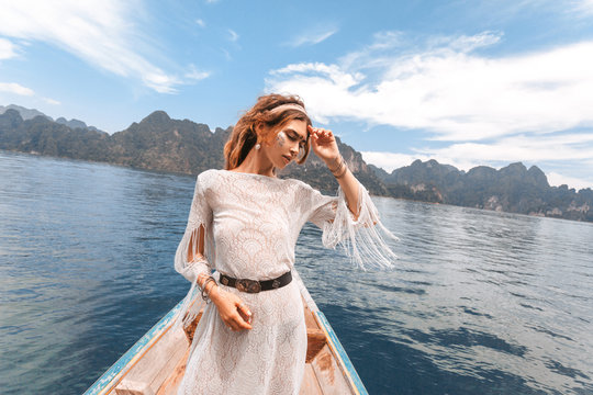 fashionable young model in boho style dress on boat at the lake
