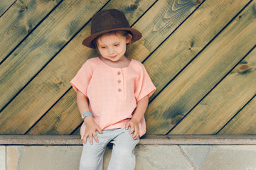Portrait of happy cute little girl in rural style brown hat and muslin clothes in a summer day on...