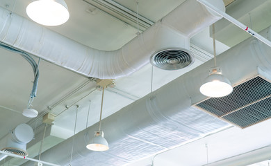 Air duct, air conditioner pipe and fire sprinkler system on white ceiling wall. Air flow and...