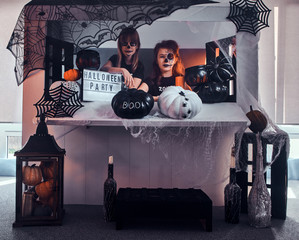 Two pensive girls with scary makeup are sitting next to traditionally decorated table.