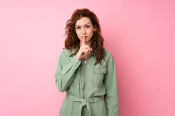 Young pretty woman over isolated pink background showing a sign of silence gesture putting finger...