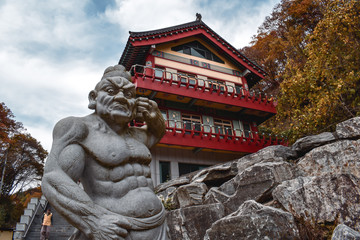 Statute of a fighting monk in front of a wooden temple building in Golgusa temple South Korea