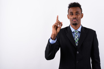 Young bearded African businessman wearing suit against white bac
