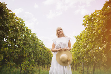 Beautiful girl in hat walking on large vineyard plantation,Tuscany, Italy.