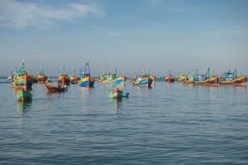 Fototapeta na wymiar Colourful Vietnamese fishing boats moored in the calm sea waters
