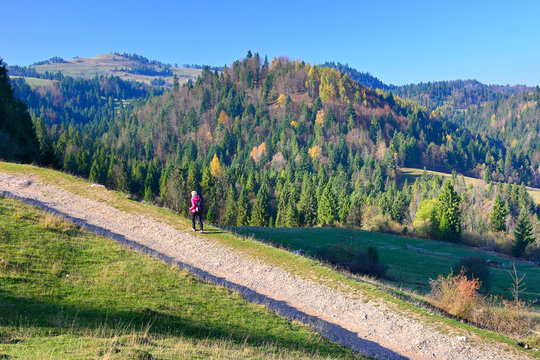 Woman backpacker on hiking trail in the mountains in autumn sunny day, Pieniny, Poland