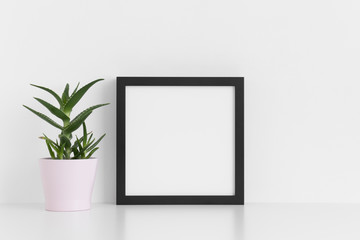 Black square frame mockup with a aloe vera in a pot on a white table.