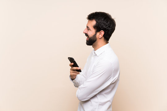 Young man with beard holding a mobile in lateral position