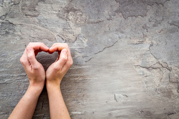 Heart icon. Hands forming a heart on grey background top view copy space