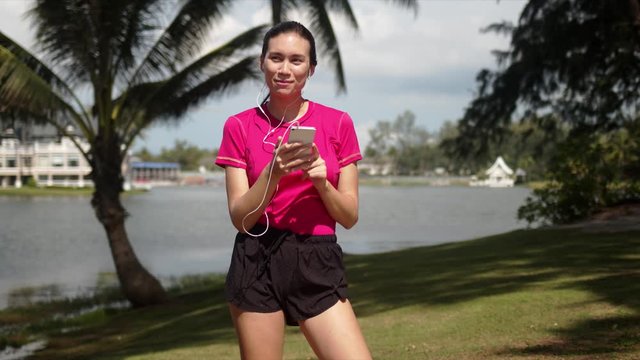 Joyful sportive woman listening to music in smartphone