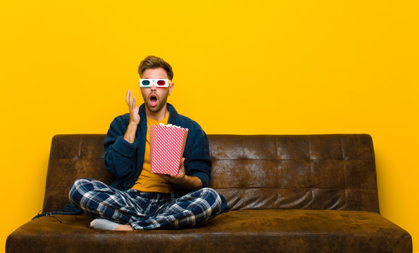 young man sitting on a sofa with popcorns. cinema concept