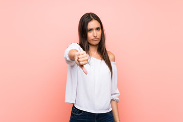 Young woman over isolated pink background showing thumb down with negative expression
