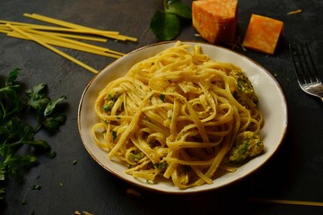 Spaghetti in a beautiful plate on a dark background. Appetizing pasta with broccoli. Noodles with cream and cheese. Homemade noodles.