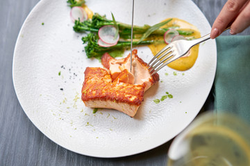 Lunch in a restaurant, a woman cuts the Salmon steak fillet and garnished with young broccoli. Restaurant menu, a series of photos of different dishes