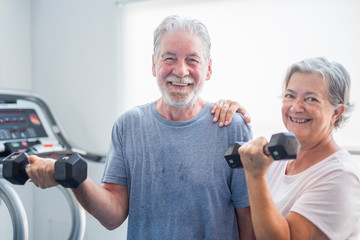 couple of two seniors at the gym holding a dumbbells and with the tapirulan at the background -...