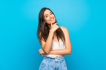 Young woman over isolated blue background smiling - obrazy, fototapety, plakaty